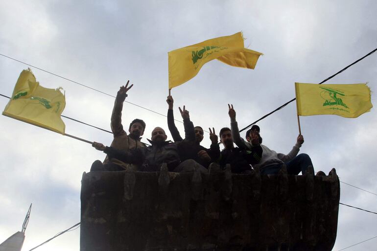 Varias personas con banderas de Hizbulá saludan este miércoles al regresar a la localidad de Nabatieh - una de las zonas evacuadas por los enfrentamientos con Israel - luego de la entrada en vigencia de la tregua.