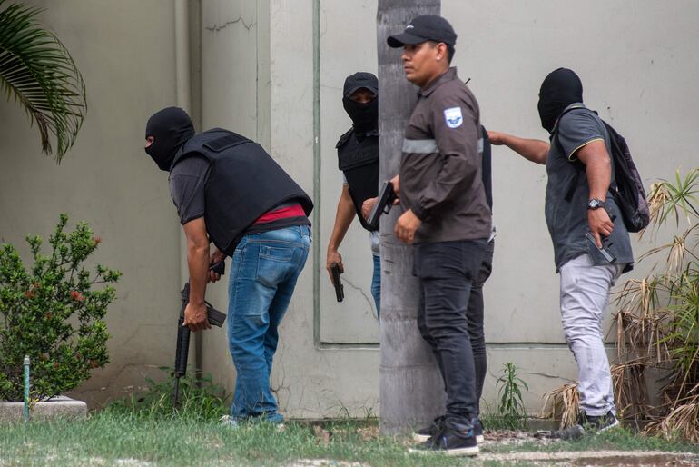 Policías realizando un operativo en la sede del canal de televisión TC, donde encapuchados armados ingresaron y sometieron a su personal durante una transmisión en vivo, en Guayaquil (Ecuador). 