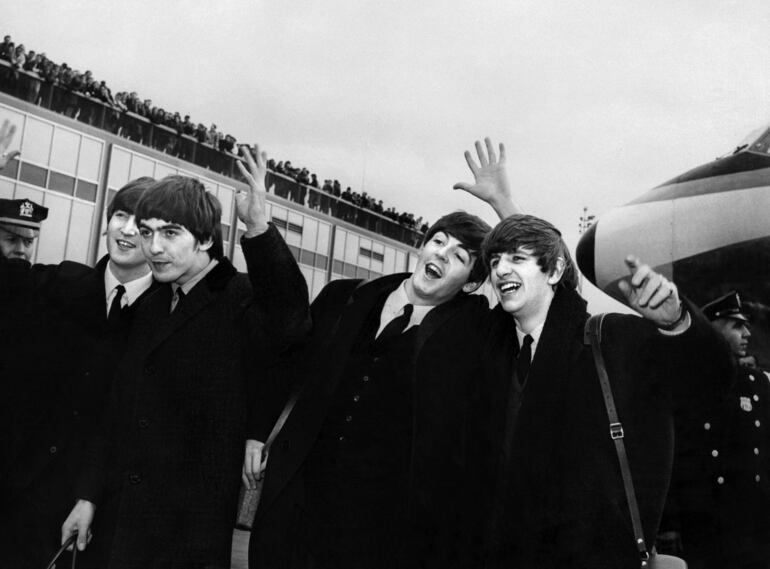 La banda inglesa The Beatles, de izquierda a derecha, John Lennon, George Harrison, Paul McCartney y Ringo Starr llegan al aeropuerto John F. Kennedy de Nueva York, Estados Unidos, donde son recibidos por una gran multitud en 1964.