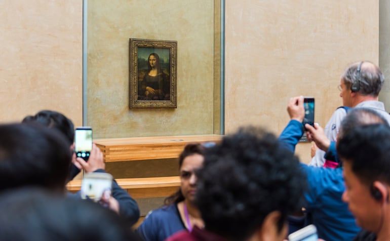 Miles de visitantes toman fotografías de la Monalisa en el Museo del Louvre en París.