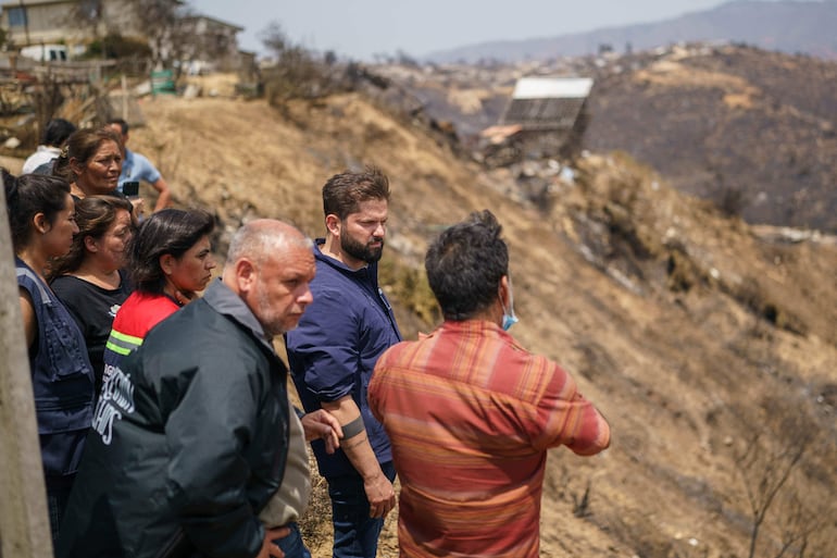 El presidente de Chile, Gabriel Boric (C), habla con los residentes de Quilpué afectados por los incendios forestales en Viña del Mar, Chile, 