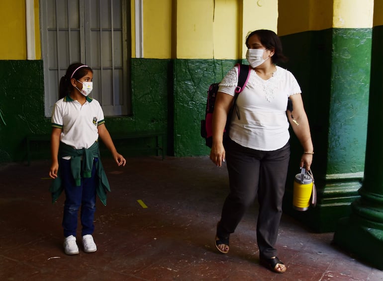 Madre e hija con el cubrebocas, en el patio de la escuela Brasil.