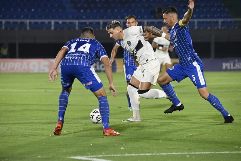 Guillermo Paiva, jugador de Olimpia, disputando el balón ante la marca de los jugadores de Sol de América.