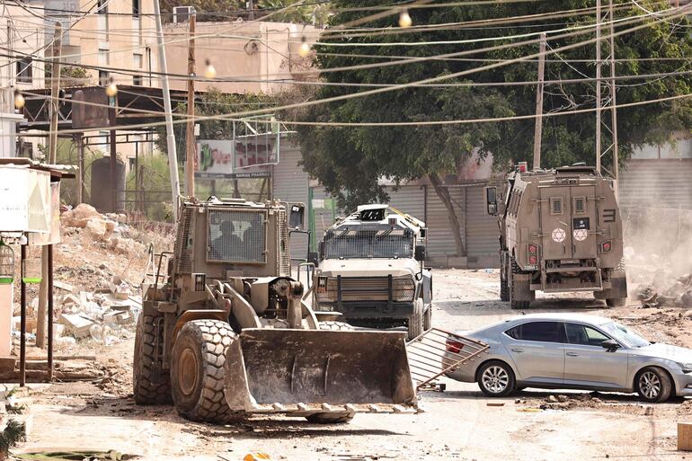 Una topadora y otros vehículos militares israelíes bloquean una calle durante una incursión en un campo de refugiados cerca de la localidad de Tubas, en Cisjordania.
