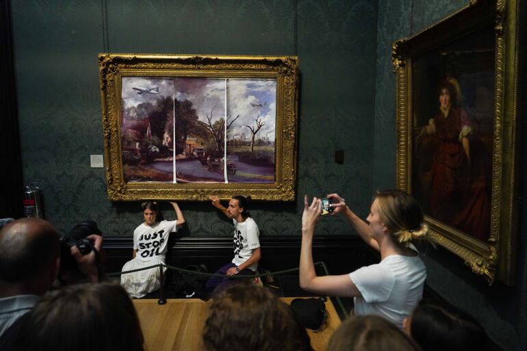 Activistas pegan con cola sus manos al marco de un cuadro de Horatio McCulloch en la galería Kelvingrove de Glasgow, junio de 2022.