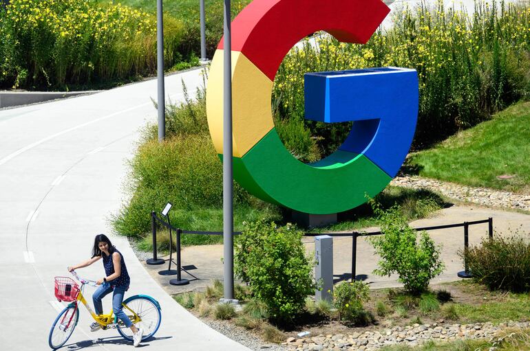 Una mujer pedalea su bicicleta junto a un logo gigante de Google, en el campus donde se realiza el evento Made by Google.