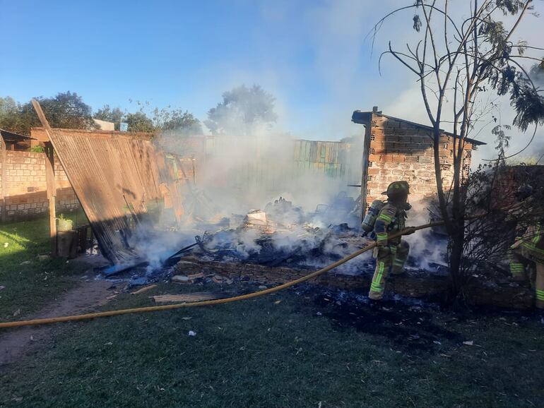 Así quedó la casa incendiada en Ciudad del Este. Un bombero realiza el trabajo de enfriamiento.