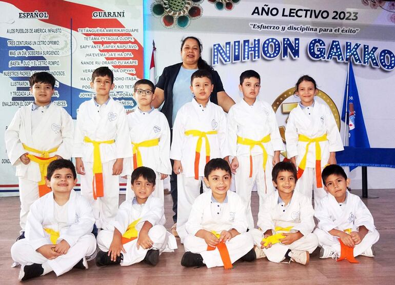 Una docente con  los alumnos que se ataron el cinturón amarillo de karate.