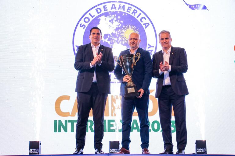 El presidente del club Sol de América, Óscar Giagni (centro) posa con el trofeo de campeón de la División Intermedia.