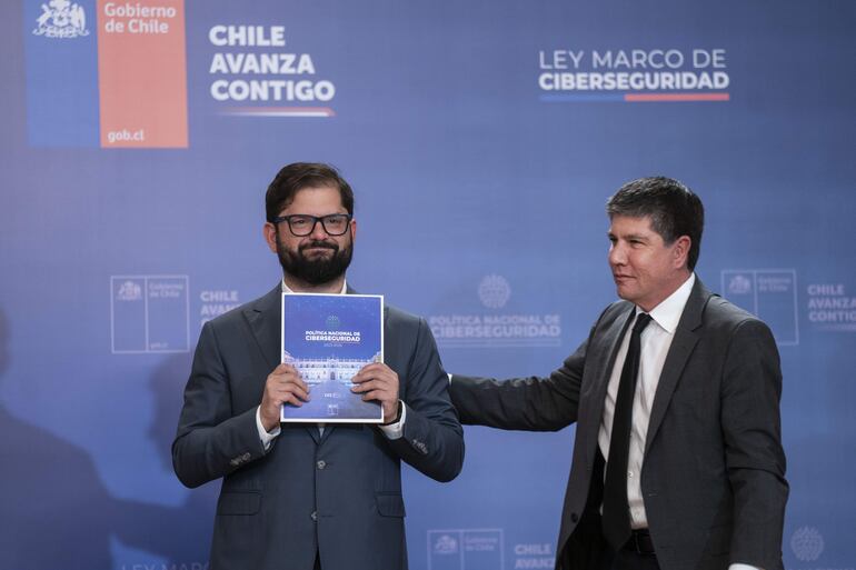 Fotografía cedida por la Presidencia de Chile que muestra al presidente Gabriel Boric (i) y al subsecretario del ministerio del Interior chileno, Manuel Monsalve (d), durante la promulgación de la Ley Marco de Ciberseguridad, en el palacio de La Moneda, en Santiago (Chile).