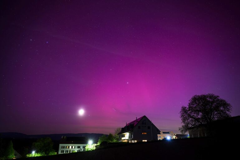 La aurora boreal brilla en el cielo nocturno sobre el pueblo de Daillens, Suiza, 11 de mayo de 2024. La Administración Nacional Oceánica y Atmosférica (NOAA) de América ha advertido que La tormenta geomagnética más fuerte en 20 años golpeará la Tierra, haciendo que la aurora boreal sea visible en latitudes geomagnéticas mucho más bajas de lo habitual. (tormenta, Suiza)