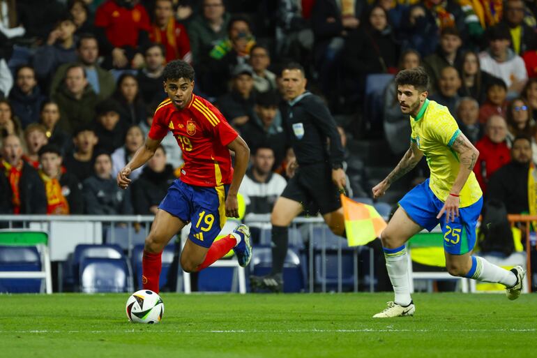 MADRID, 26/03/2024.- El delantero de la selección española Lamine Yamal (i) disputa un balón frente a Lucas Beraldo, defensa de la selección brasileña, durante el partido amistoso que las selecciones nacionales de fútbol de España y Brasil disputan hoy martes en el estadio Santiago Bernabéu, en Madrid. EFE/Mariscal
