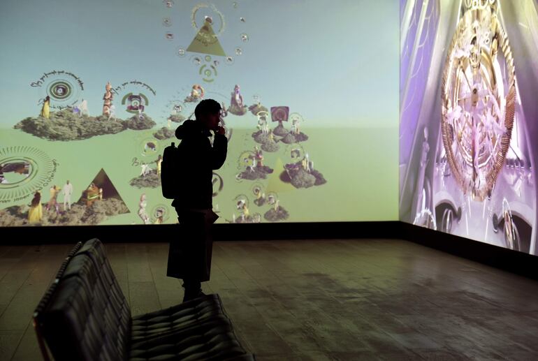 Un miembro de los medios observa las obras del artista estadounidense Jacolby Satterwhite durante una vista previa para la prensa de la exposición "Machine Love: Video Game, AI and Contemporary Art" en el Museo de Arte Mori en Tokio, Japón.