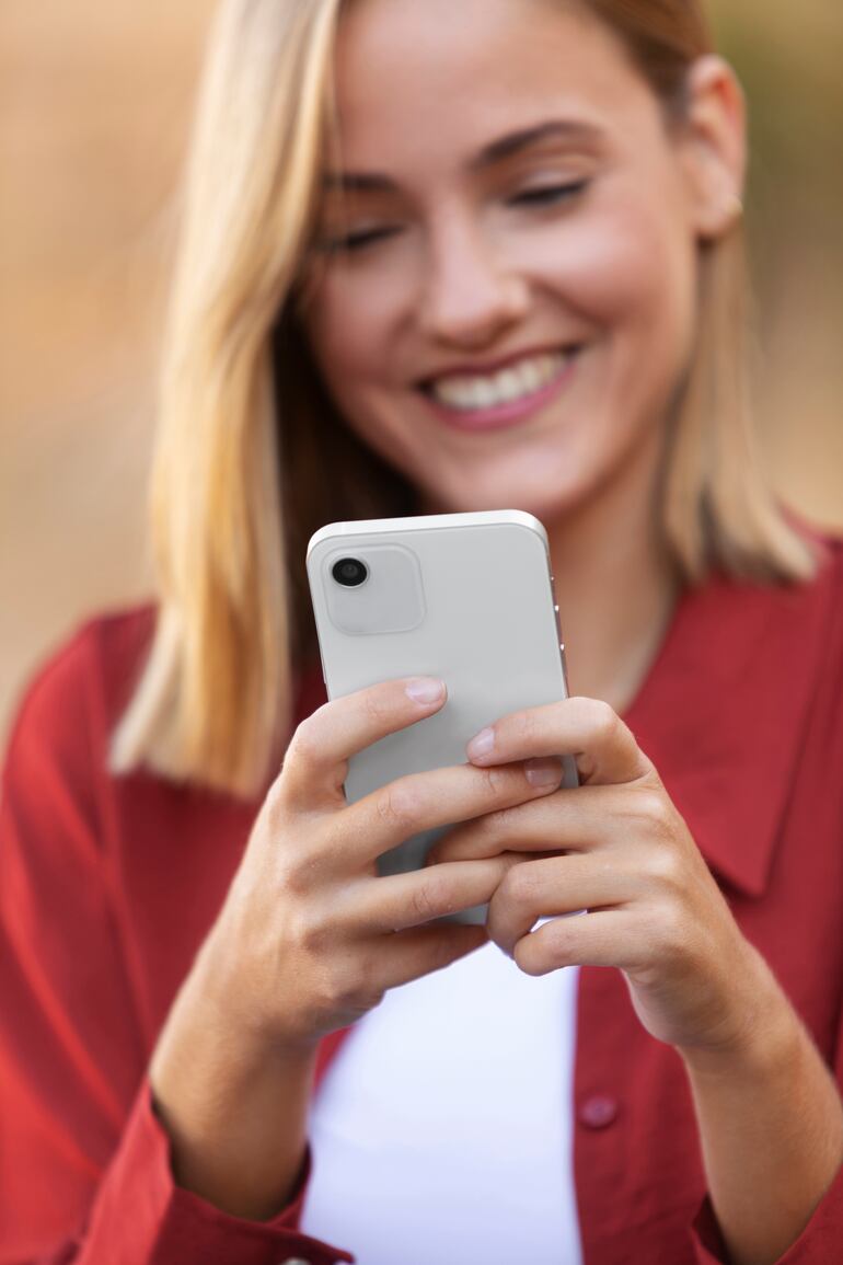 Joven sonriente utilizando un teléfono inteligente de última generación.