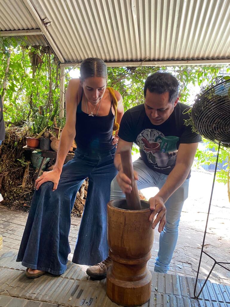 Juanita Viale mira atentamente cómo Javier Torres prepara el pohã ñana en un mortero para luego tomar un refrescante tereré. (Facebook/Javier Torres)