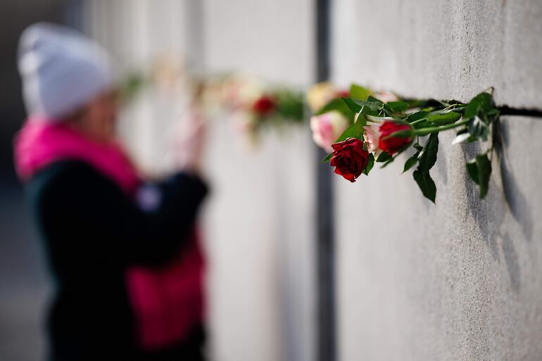 Una persona deja flores en los restos del Muro de Berlín, este sábado.