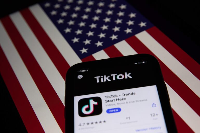 Un teléfono celular con la aplicación china de medios de Internet TikToky una bandera de EE. UU. en la pantalla de una computadora portátil, en Pekín (China). La recopilación de datos de los usuarios por parte de TikTok convierte a esa plataforma en una amenaza para la seguridad nacional, dijo el viernes el Departamento de Justicia de Estados Unidos en respuesta a una demanda civil de la empresa de propiedad china destinada a evitar la venta forzada de la aplicación.