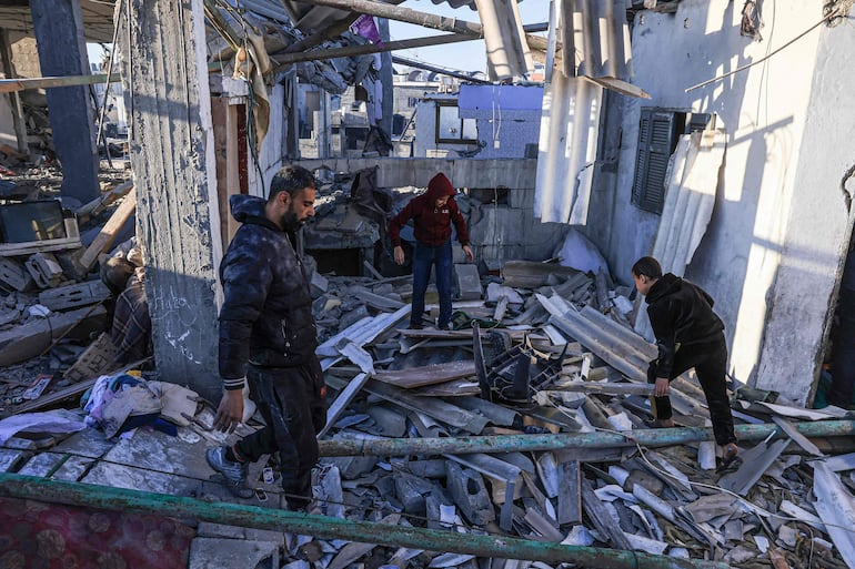 Tres personas buscan entre escombros luego de un bombardeo israelí en Rafah, en el sur de la Franja de Gaza, este martes.