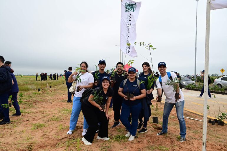 Un grupo de jóvenes posa con los pequeños árboles nativos antes de plantarlos en la  Costanera Sur.