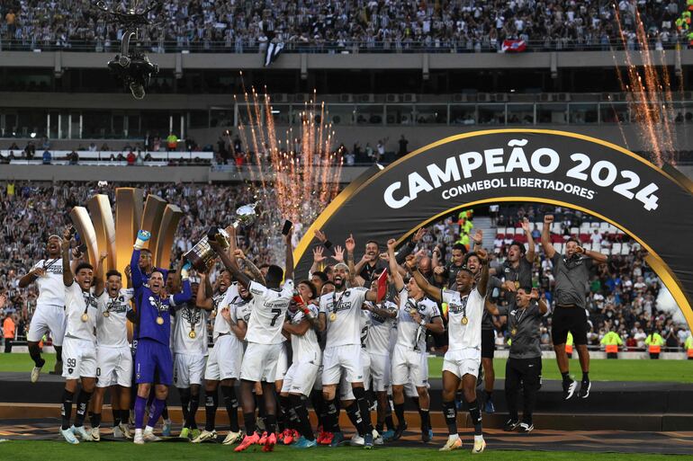 Botafogo's players celebrate with the trophy after winning the Copa Libertadores final football match between Brazilian teams Atletico Mineiro and Botafogo at the Mas Monumental Stadium in Buenos Aires on November 30, 2024. (Photo by Luis ROBAYO / AFP)