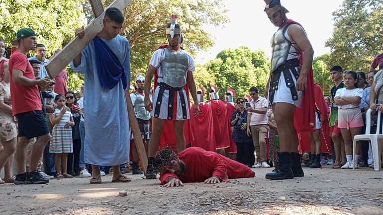 Simón de Cirene sostiene la pesada cruz de Jesús, que agoniza en el suelo de tanto dolor.