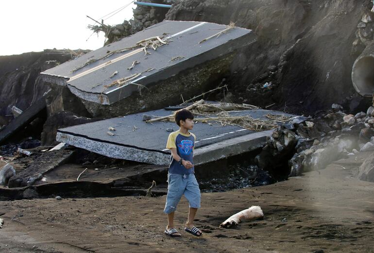 Un niño camina junto a los restos de un puente dañado por el temporal en la localidad de Laurel, Filipinas, el domingo.