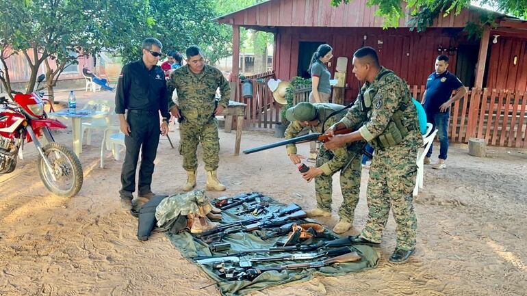 El fiscal Pablo Zárate,  vestimenta negra, y policías verifican las armas encontradas tras investigación de ganados presuntamente robados.