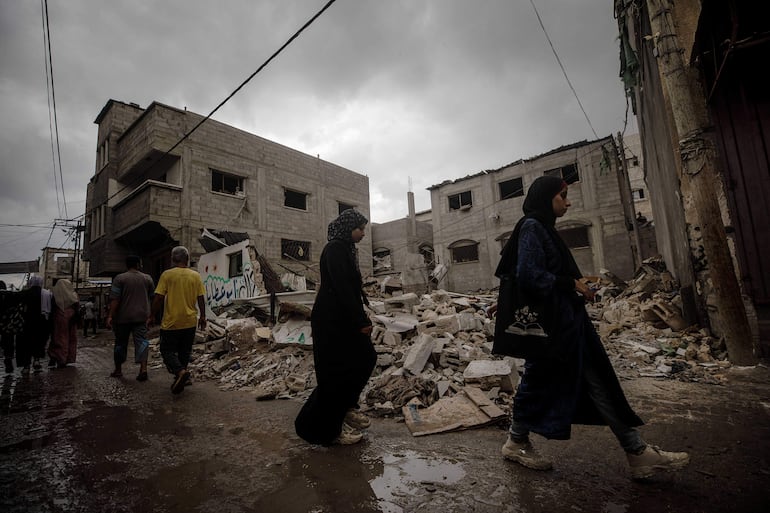 Varias personas caminan cerca de una casa destruida en un bombardeo israelí, el martes en el campo de refugiados de Nuseirat, en el centro de la Franja de Gaza.