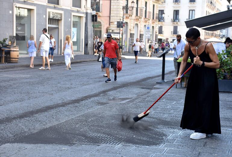 Un residente de Catania barre el suelo cubierto con una capa de ceniza volcánica negra, en Catania, Sicilia, Italia
