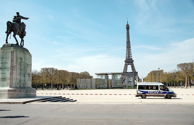 Una solitaria patrulla policial ante la torre Eiffel, el lugar más concurrido de París, hoy desierto en medio de la cuarentena en esa ciudad, así como en prácticamente todo el mundo, que aun no ve con claridad cómo encarar la reactivación de las actividades.
