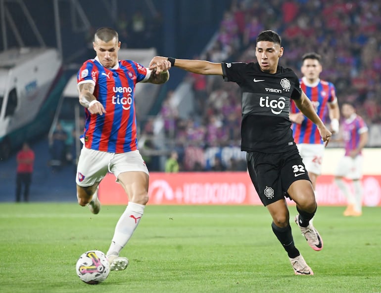 Alan Benítez (i), jugador de Cerro Porteño, y Erik López, futbolista de Olimpia, pelean por el balón en el superclásico por la sexta fecha del torneo Clausura 2024 del fútbol paraguayo en el estadio La Nueva Olla, en Asunción.