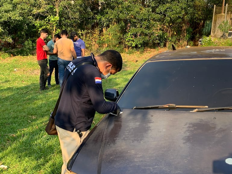 Perito del Departamento de Criminalística inspecciona el auto de las víctimas para tratar de encontrar huellas dactilares .