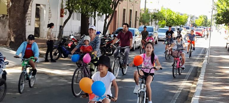 Niñas y niños participantes de la colonia de vacaciones realizan un paseo en bicicleta por el centro de Pilar.