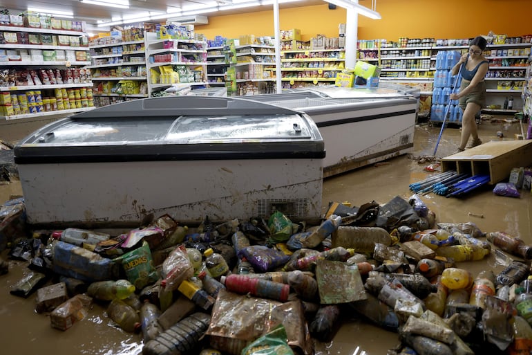 Una mujer retira el lodo acumulado en su comercio en Picanya, Valencia, este jueves, tras la DANA.