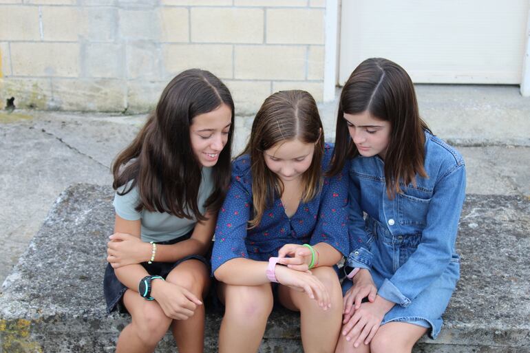 Tres niñas llevando relojes inteligentes con geolocalización por GPS.