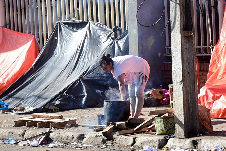 Una mujer prepara la olla popular para el almuerzo de su familia frente al Indi.