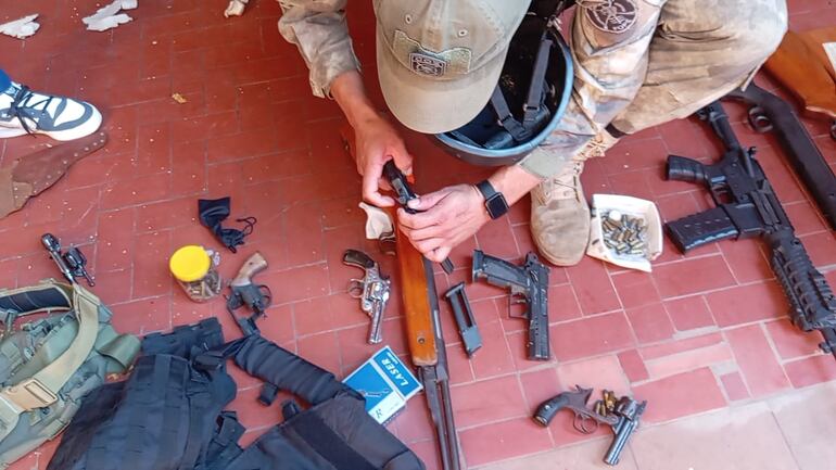 Un efectivo de la FOPE inspecciona uno de los rifles encontrados en la vivienda allanada, ubicada en el centro de Asunción.