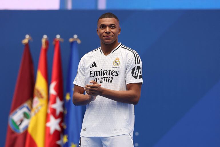 TOPSHOT - French forward Kylian Mbappe looks on during a first appearance as a Real Madrid player before fans at the Santiago Bernabeu Stadium in Madrid on July 16, 2024, after signing his new five-season contract. Still celebrating Spain's Euro 2024 triumph, Real Madrid fans have even more to cheer this July 16, 2024, as French superstar Kylian Mbappe is officially presented to a packed-out Santiago Bernabeu stadium. (Photo by Pierre-Philippe MARCOU / AFP)