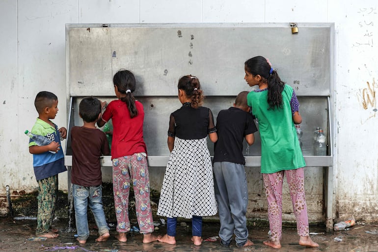 Niños llenan botellas de agua en un refrigerador en una aldea beduina cerca de Beit Lahia, en la Franja de Gaza, el pasado 28 de agosto.