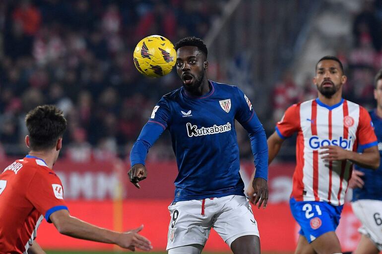 Iñaki Williams, delantero del Athletic Bilbao, mira fijamente el balón ante el acoso de dos jugadores de Girona.