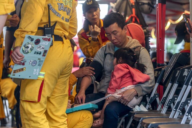 Un hombre que lleva a un niño recibe atención médica en un puesto de mando de rescate temporal después de ser rescatado del Parque Nacional Taroko en Hualien el 5 de abril de 2024 tras el terremoto del 3 de abril.