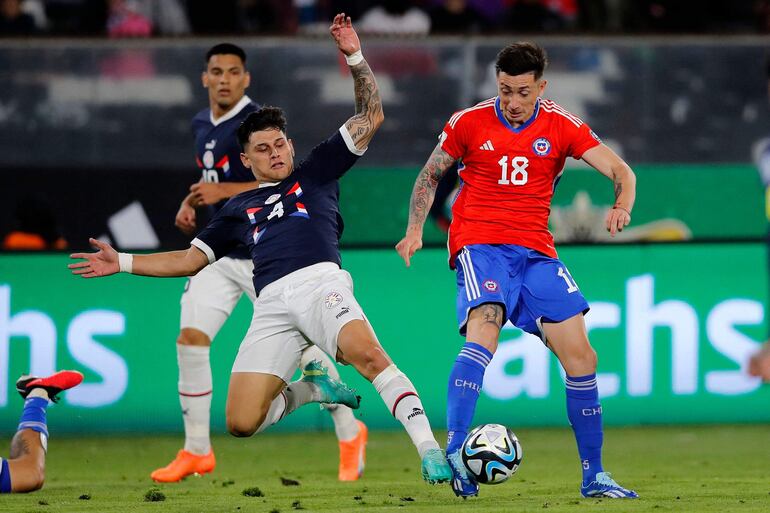 Matías Espinoza (i), futbolista de la selección paraguaya, pelea por el balón en el partido frente a Chile por las Eliminatorias Sudamericanas al Mundial 2026 en el estadio Monumental, en Santiago, Chile.