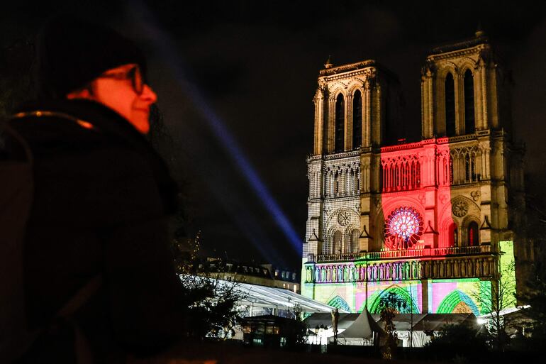 Una mujer observa la fachada de la catedral Notre-Dame de París (Francia). La catedral de París se inaugurará oficialmente el 7 de diciembre de 2024, tras casi seis años de obras de renovación. 