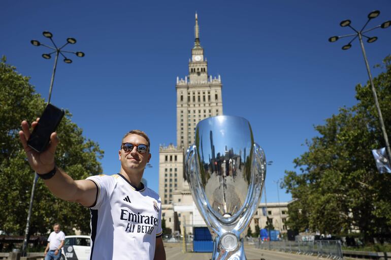 Aficionado del Real Madrid realiza una selfie junto una réplica del trofeo de la Supercopa de Europa junto a la Torre de la Ciencia de Varsovia, en Polonia. 