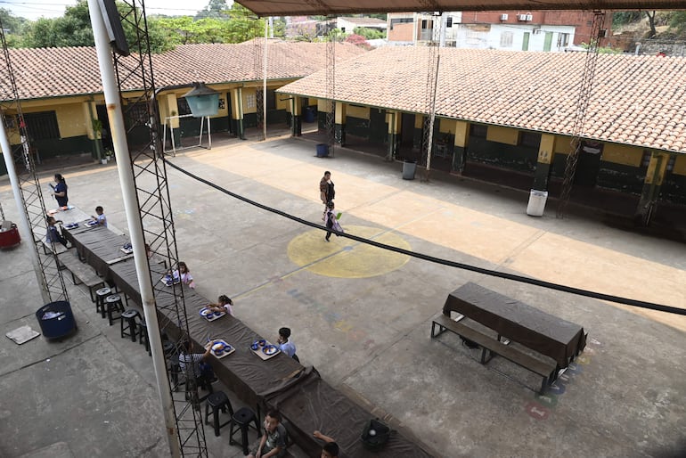 Una larga mesa de tablones se extiende bajo un tinglado para el almuerzo de los alumnos, en una escuela de Asunción.