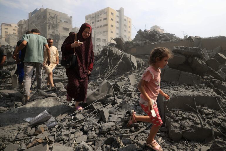 Una mujer y una niña caminan entre los escombros de una mezquita destruida por un ataque aéreo israelí en la Ciudad de Gaza, este lunes.