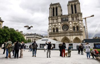 La gente se encuentra frente a la Catedral de Notre-Dame, en París. Notre Dame de París, cuyo tejado sufrió un voraz incendio en 2019, reabrirá al público el 8 de diciembre con un mobiliario moderno y un vestuario litúrgico totalmente rediseñado.