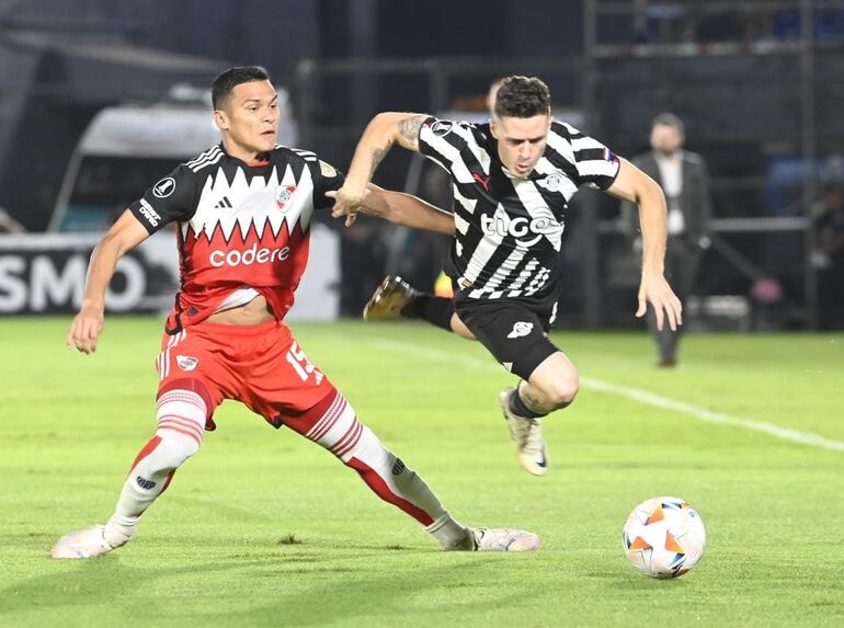 El argentino Bautista Merlini (d), jugador de Libertad, pelea por el balón en un partido frente a River Plate por la Copa Libertadores 2024 en el estadio Defensores del Chaco, en Asunción, Paraguay.