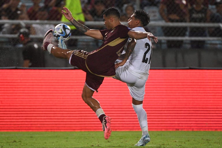 TOPSHOT - Venezuela's defender Miguel Navarro (L) and Uruguay's midfielder Facundo Torres fight for the ball during the 2026 FIFA World Cup South American qualifiers football match between Venezuela and Uruguay at the Monumental stadium in Maturin, Venezuela, on September 10, 2024. (Photo by Federico Parra / AFP)