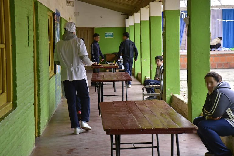 Estudiantes almuerzan con tablones en un pasillo en una escuela de Lambaré.